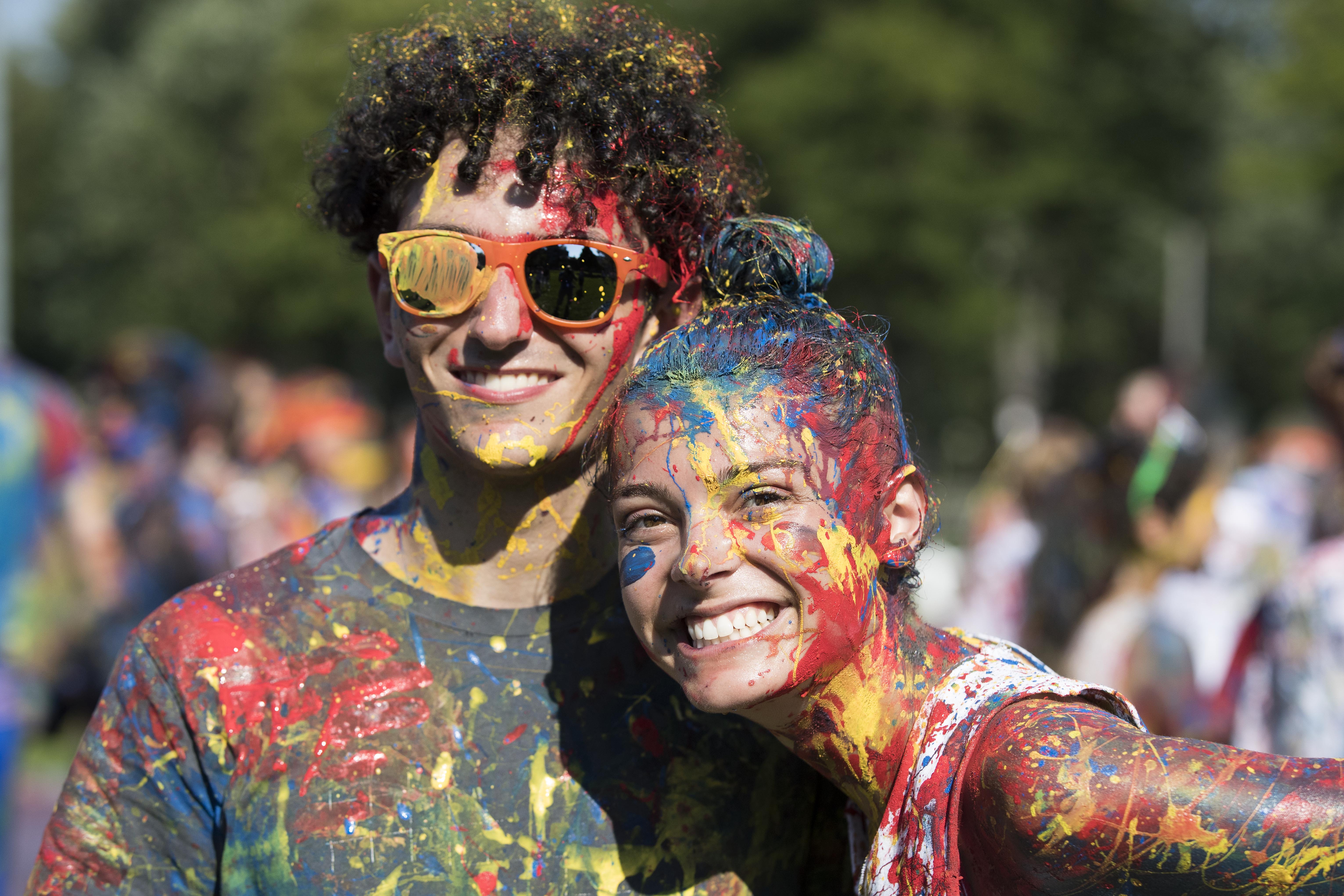 Two Queen's students smiling with tricolour paint on them.