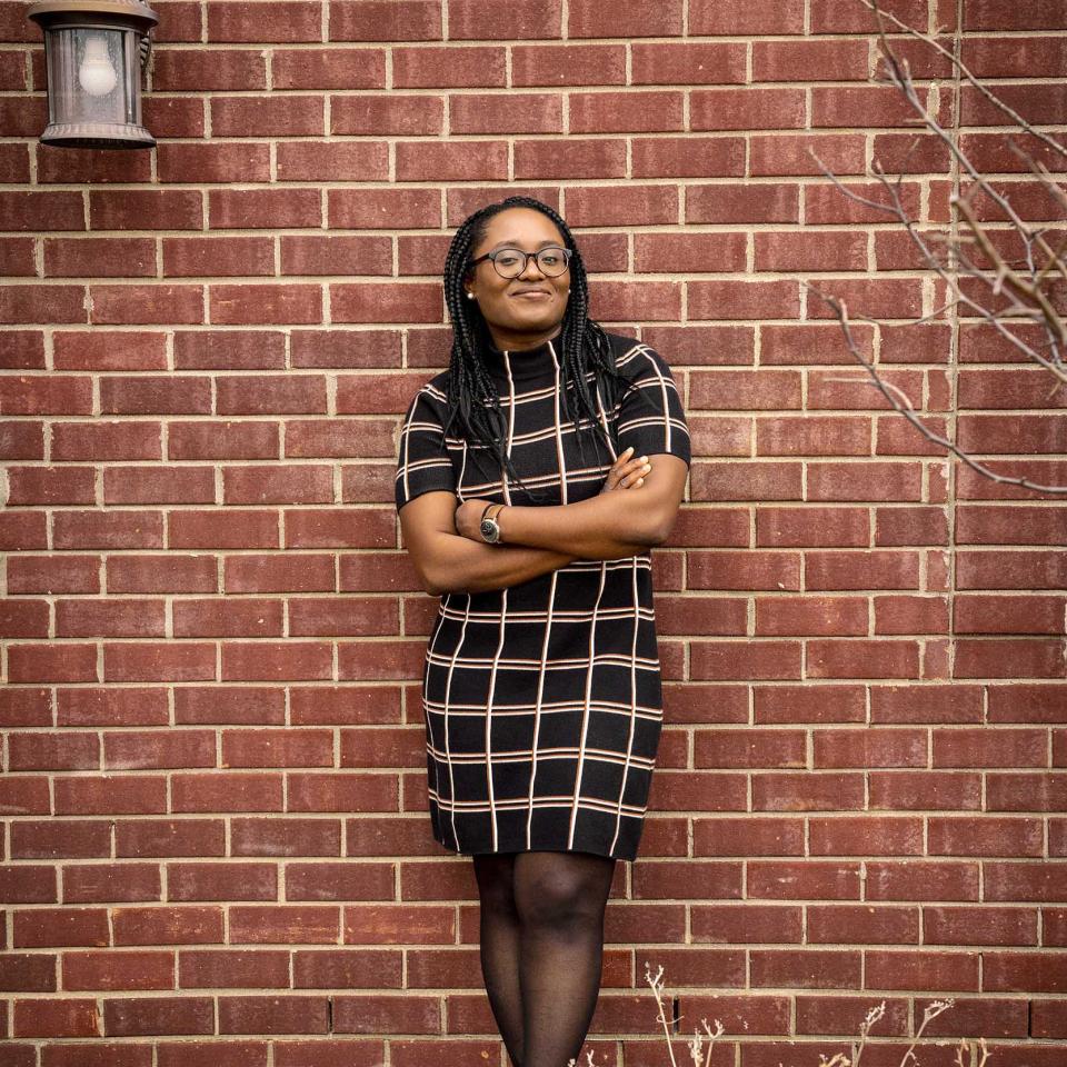 Dr. Idara Edem leaning against a brick wall with her arms crossed in front of her.