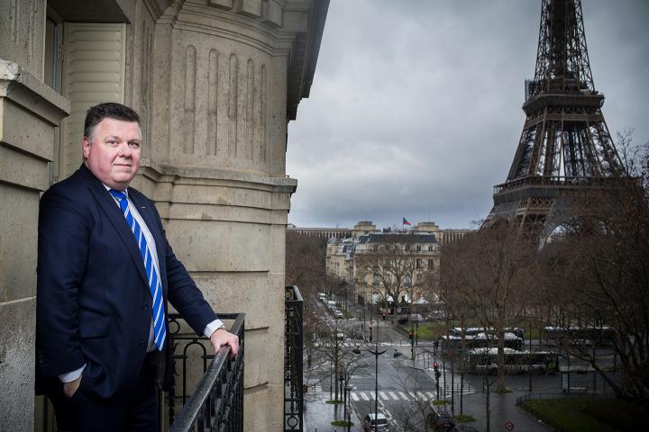 Andrzej Antoszkiewicz stands on a balcony that overlooks the Eiffel Tower.