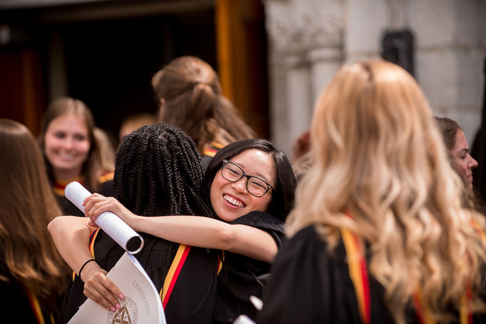 Two students hugging after graduating from Queen's University