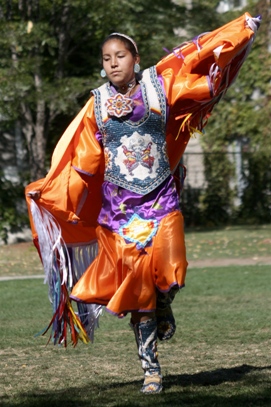 An Indigenous woman dancing in ceremonial dress at a Powwow hosted at Queen's University. 