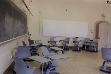 View from the side of the room: Moveable chairs with attached tablet tables in a room with beige walls.