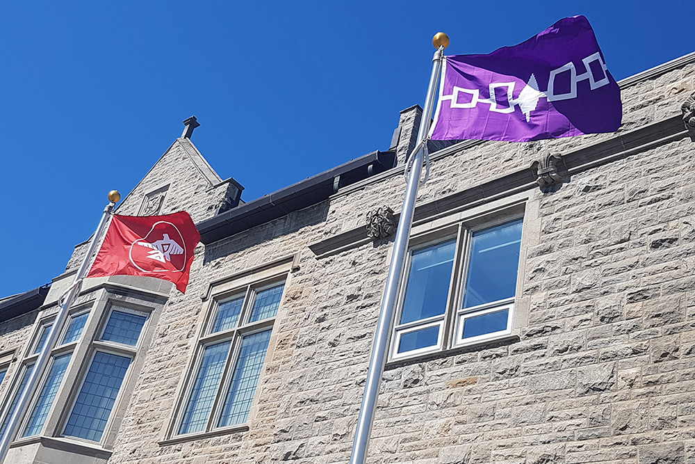 Anishinaabe and Haudenosaunee flags flying in front of Richardson Hall