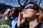 Three Queen's students wearing eclipse glasses