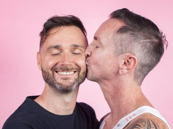 Image of one man kissing another on the cheek with the hashtag love is love