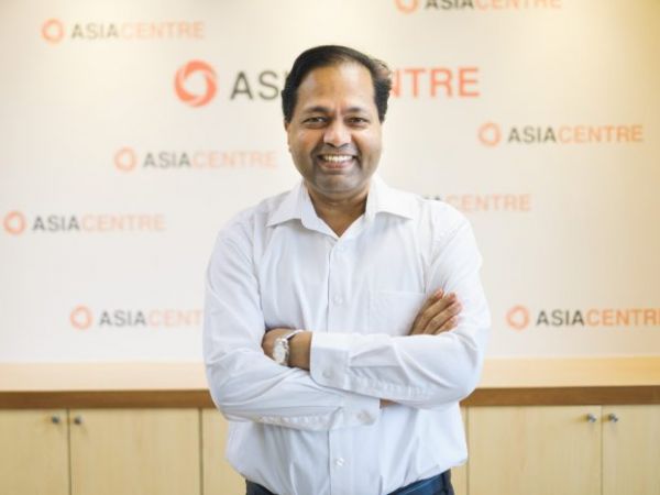 Image of Robin smiling in front of a background that reads Asia Centre