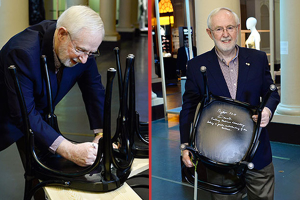 Professor Emeritus and Nobel Laureate Art McDonald follows a tradition by autographing a chair at Bistro Nobel at the Nobel Museum in Stockholm.