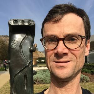 Photo of Glenn Willmott beside a Miro sculpture