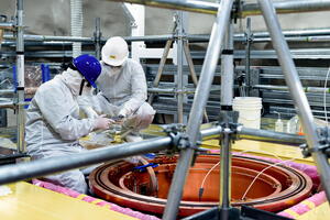 Two scientists crouch on top of the SuperCDMS experiment during construction