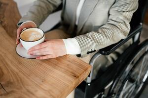 woman in wheelchair with a cup of coffee at table