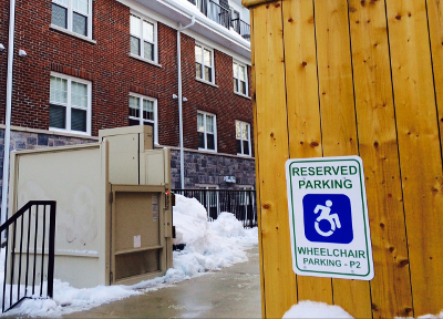 photo outside property showing accessible parking sign and wheelchair lift