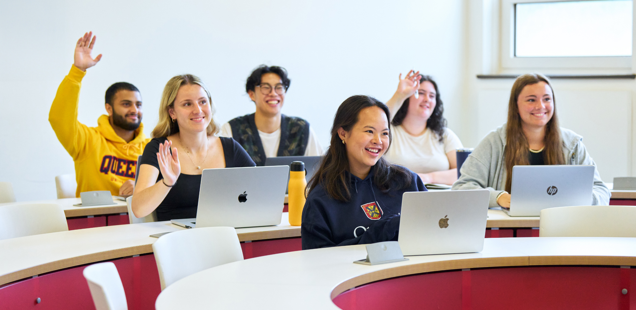 Students in a class raising thier hands