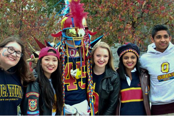QSAA volunteers pose for a photo with Queen's Superfan. Links to QSAA Website.
