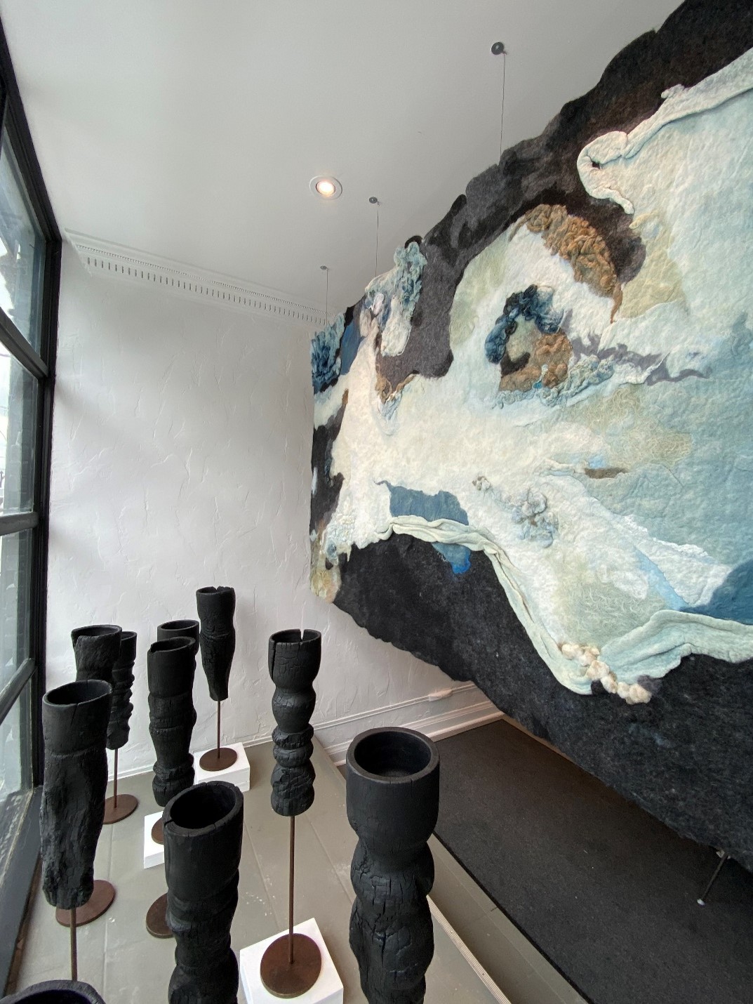 An art piece resembling waves of Lake Ontario created from felt hangs in a gallery.