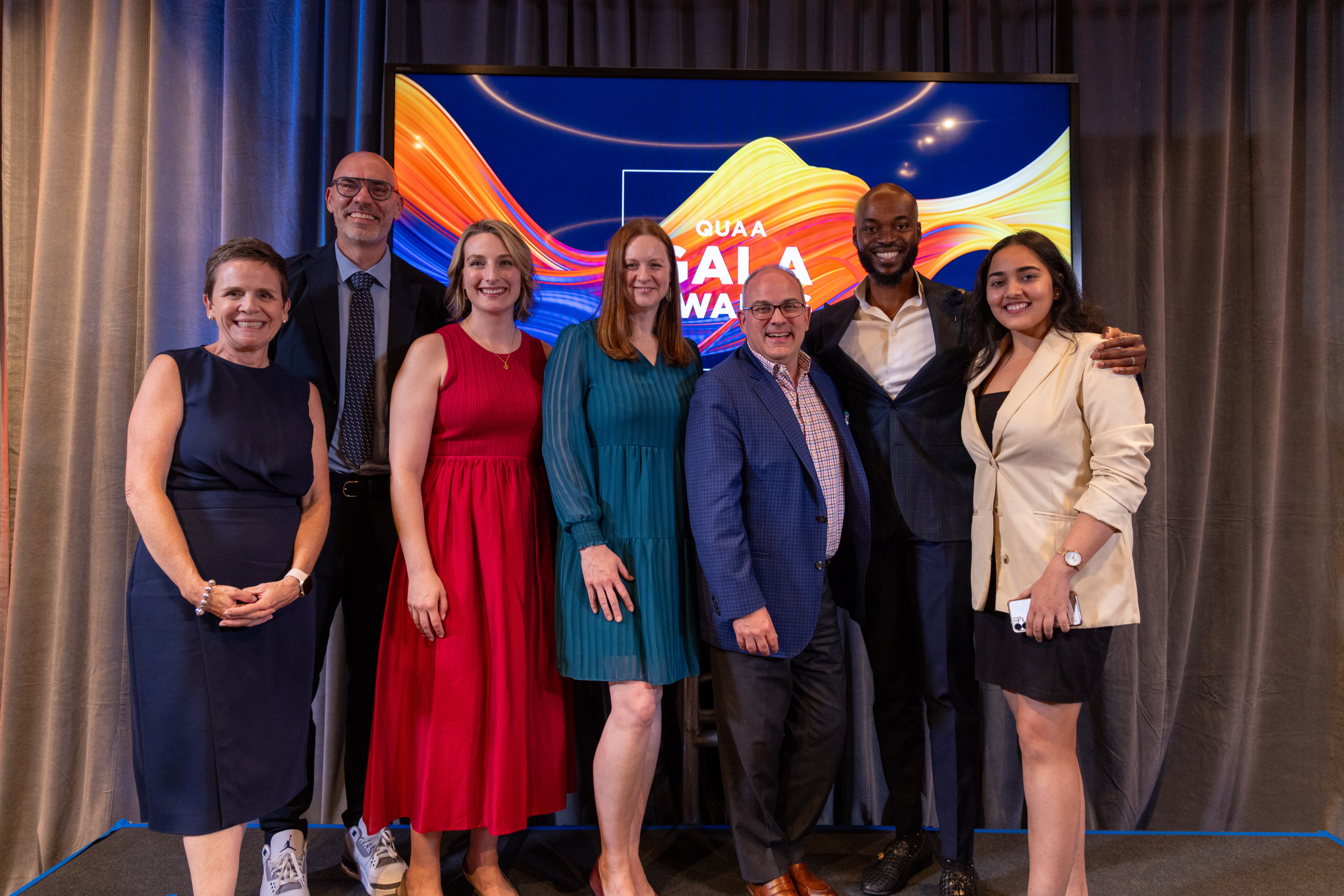 Several members of the QUAA board gather at the 2026 QUAA Gala Awards. From left: Kelly McKinley, Artsci’91; Gareth Gibbins, Com’00, MIR’01; Allison Williams, Artsci’09; Julie Nixon, Com’99; Stacy Kelly, Artsci’93; Akin Akinsipe, MBA’19; and Tamanna Chuhan, MIB’23. (Photo: Callum Linden)