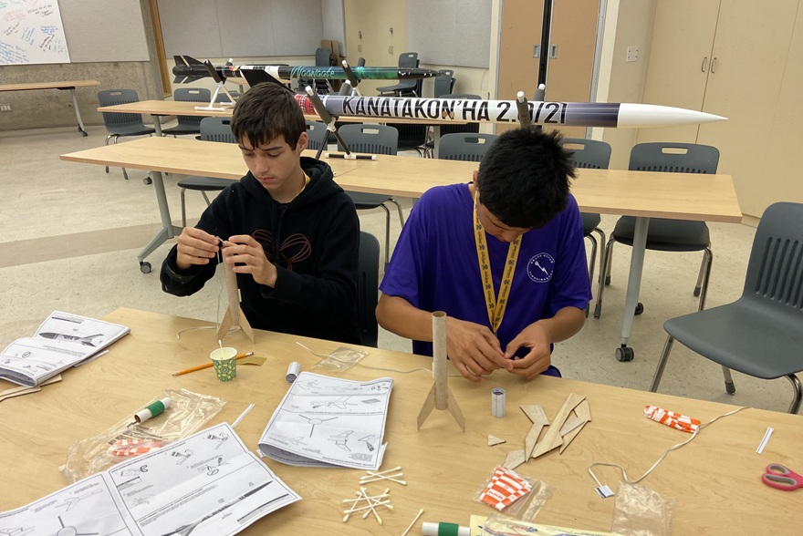 Two academy participants work on building model airplanes. 