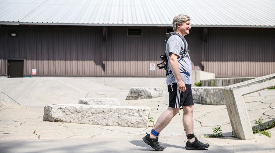 Michael Shepertycky wearing his patented exoskeleton, walking in front of a building.