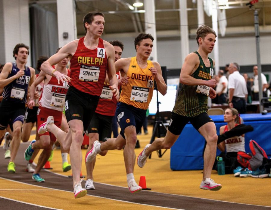 A group of professional young runners in a tracked with a roof.