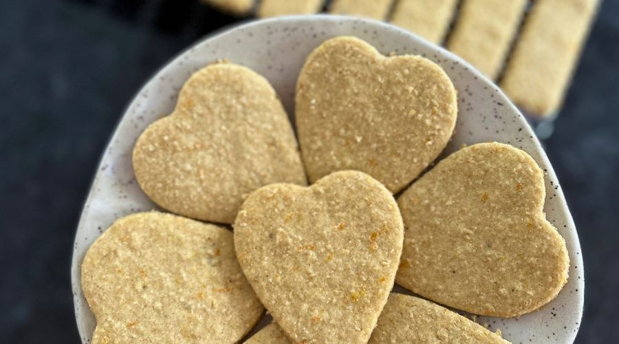 A plate of heart-shaped orange cardamom cookies arranged neatly, showcasing their golden-brown color and delicate texture.