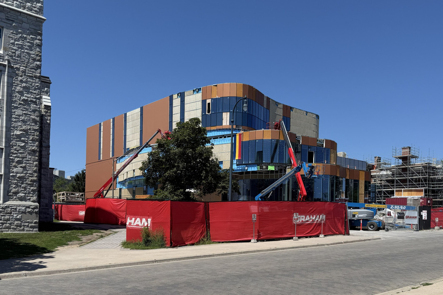 An under-construction building at a street corner, with construction equipment and materials, captured in August 2026.