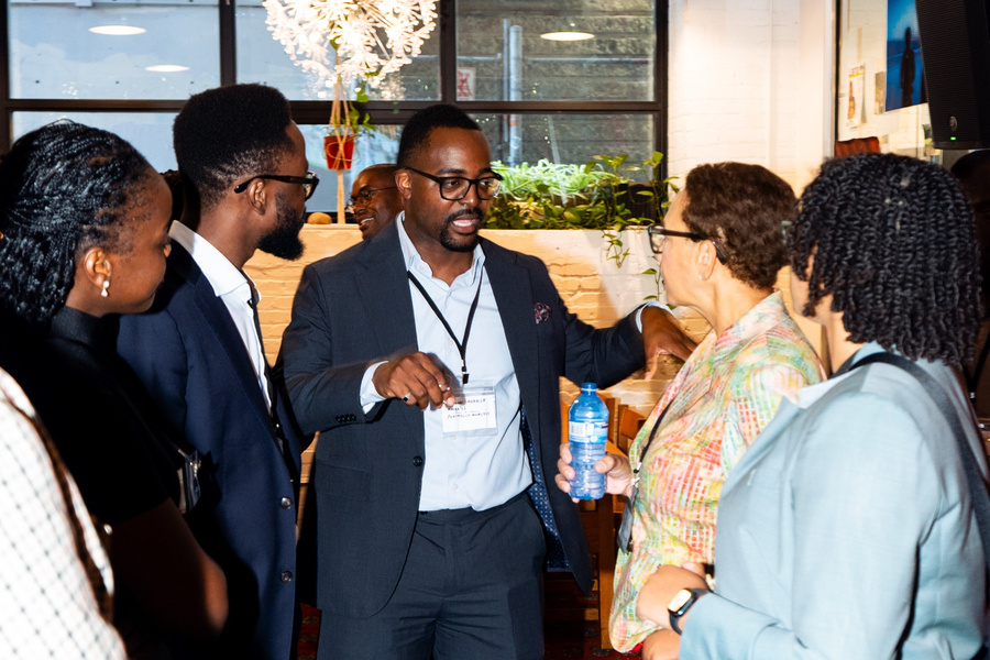 A group of five people engaged in conversation, standing together in a casual setting.
