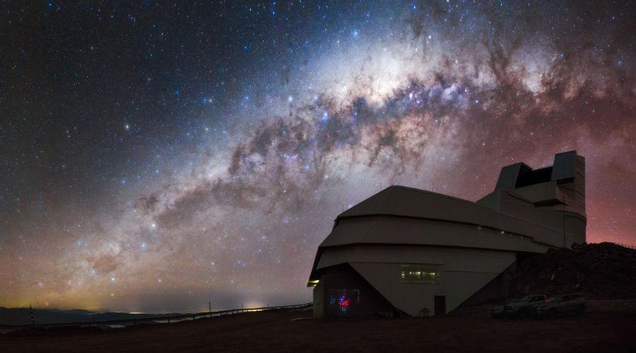 The Milky Way arcs over the Rubin Observatory, with the Magellanic Clouds glowing in the night sky.