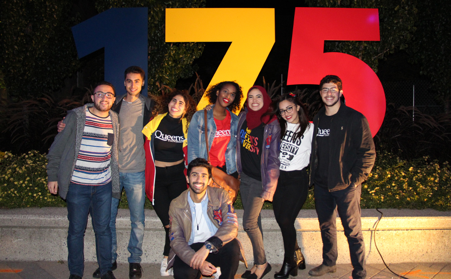Alumni standing in front of the Homecoming 175 Monument, smiling and posing together for the photo.
