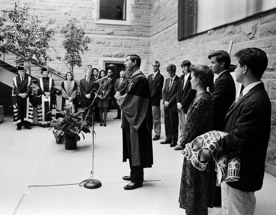 Prince Charles speaks at the JDUC in October 1991, surrounded by attendees, one holding a sweater for him.