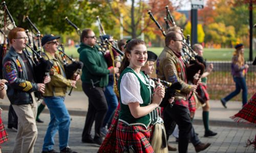 Students and alumni walking next to the band on the Homecoming Parade.