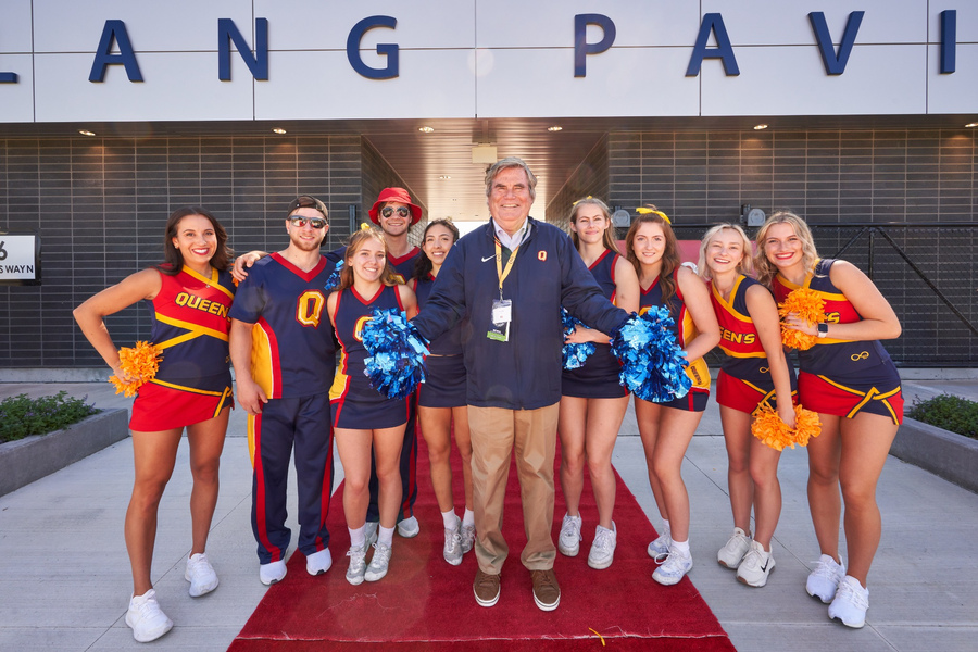 Stu Lang poses with Queen's cheerleaders in front of the Lang Pavilion during its opening in September 2023.