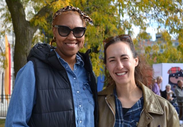 Johnelle Lanham and Kendra Hartley smile for the camera in front of a lush green tree.