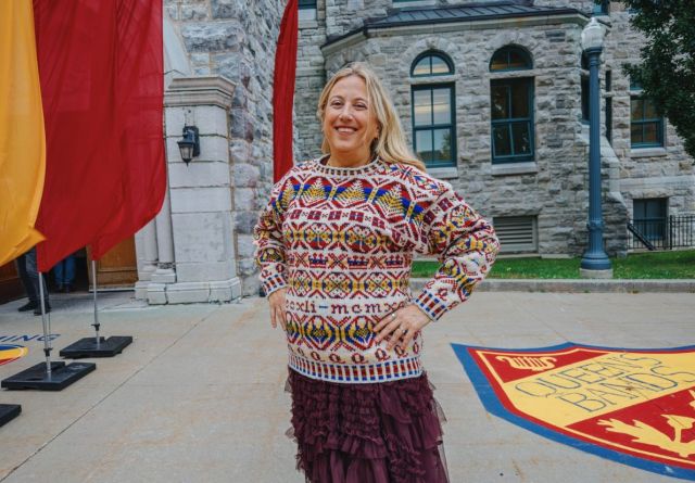 Allison Thistlewood, wearing a vibrant Homecoming 100 sweater, poses in front of Grant Hall.