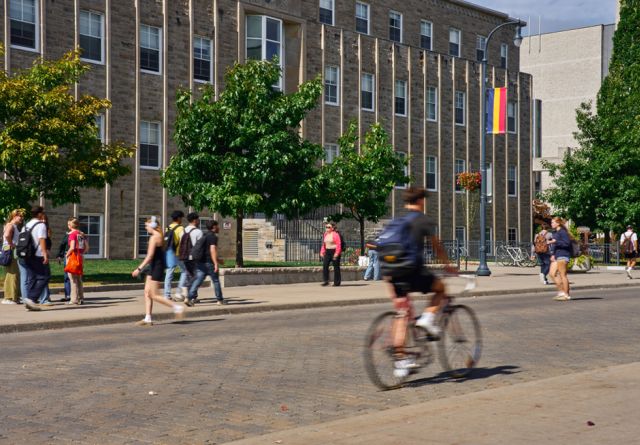 A large academic building on the Queens University campus, showcasing modern architecture and surrounding greenery.