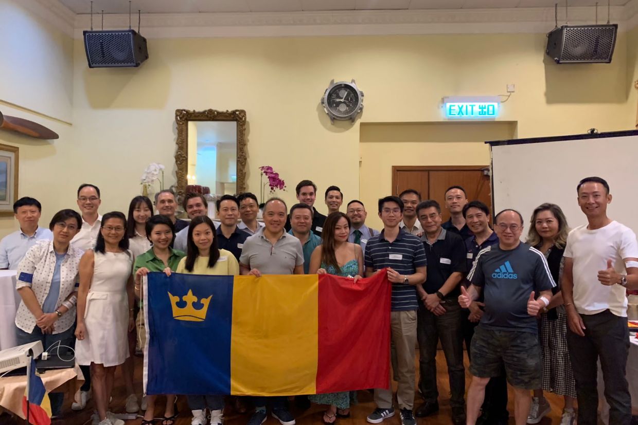 Queen's alumni in Hong Kong standing and holding the Queen's tricolour flag.