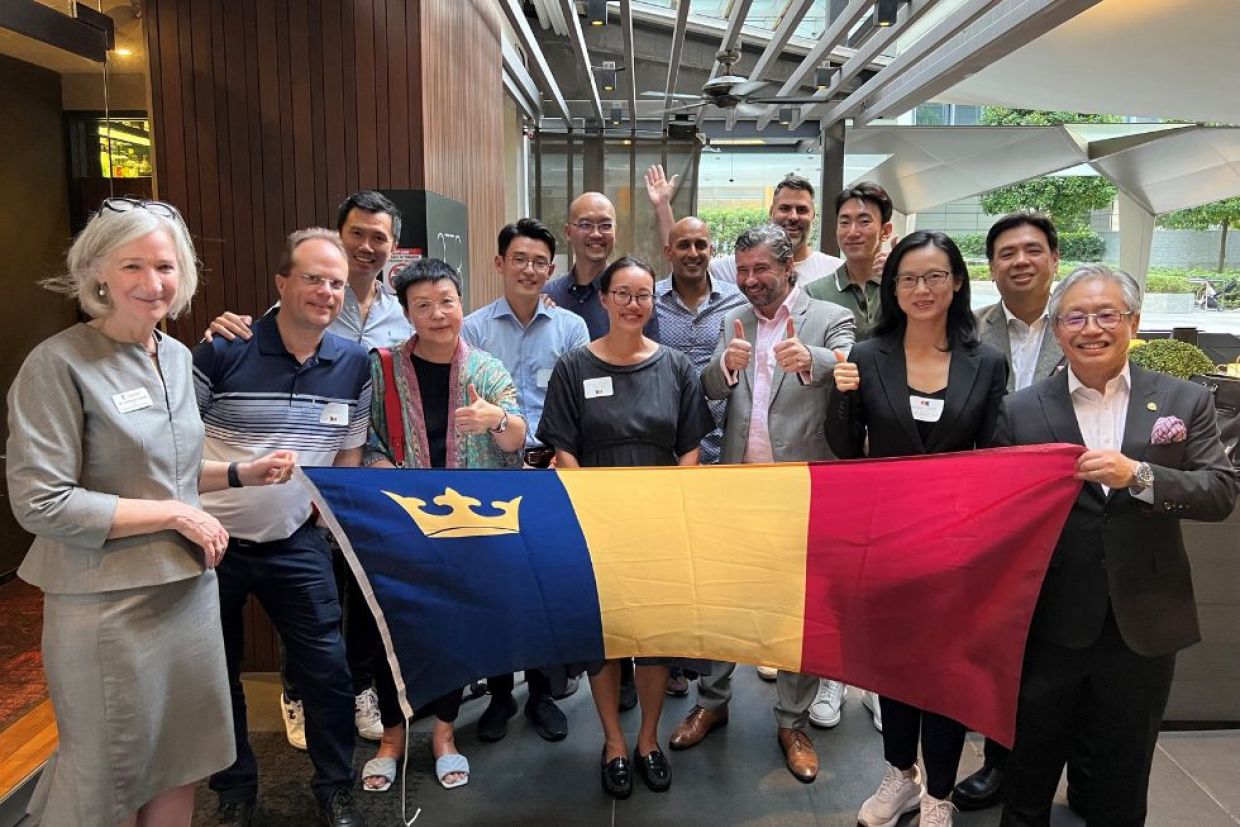 Alumni holding the Queen's tricolour flag at an event.