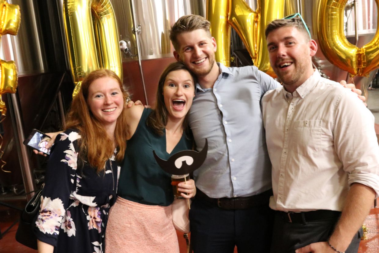 Youthful alumni laugh and pose for a photo.