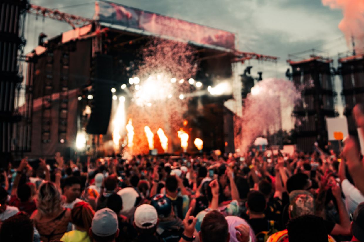A crowd at a music fesitval watches the stage performance.