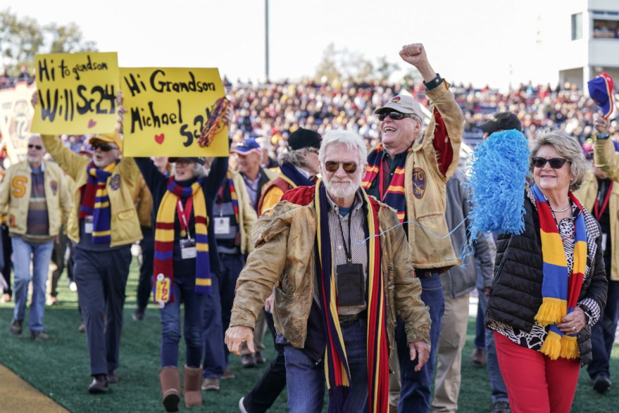 Members of Tricolour Guard parade around Richardson Stadium. Some holds signs for their grandchildren attending Queen's.