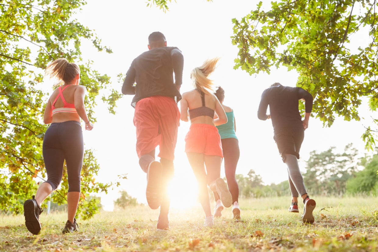 A diverse group of people jog along a path on a spring day.