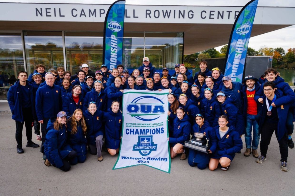 The rowing team from Ontario University Athletics stands together for a photo in front of their building, showcasing team spirit.