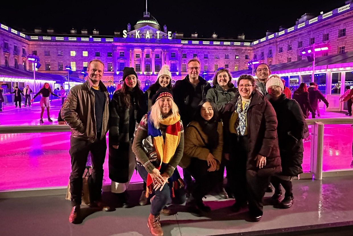 A cheerful group of Queen's alumni poses in front of a building at the Annual Skate in London, UK.