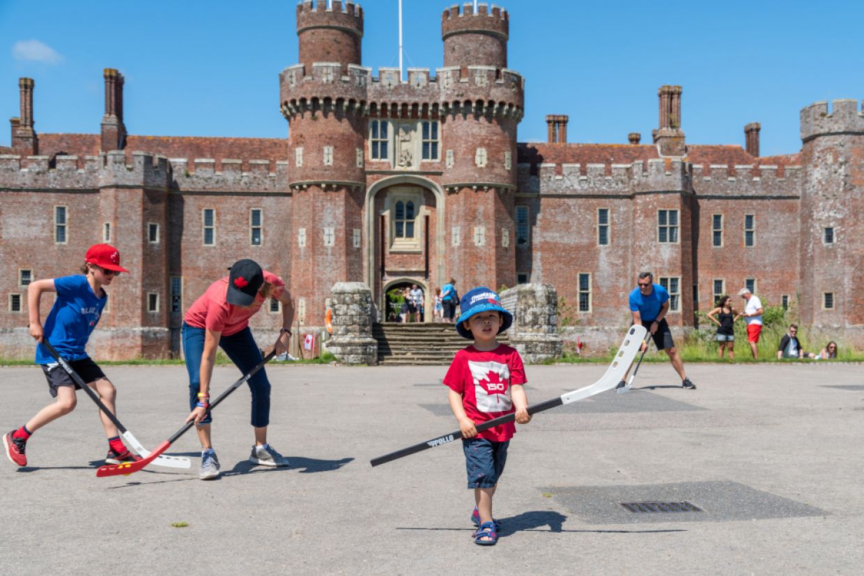 Alumni and children play road hockey outside Herstmonceux Castle