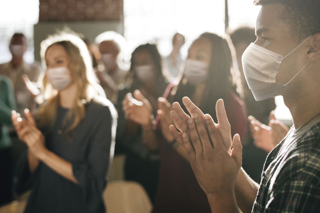 Audience applauding while wearing medical masks