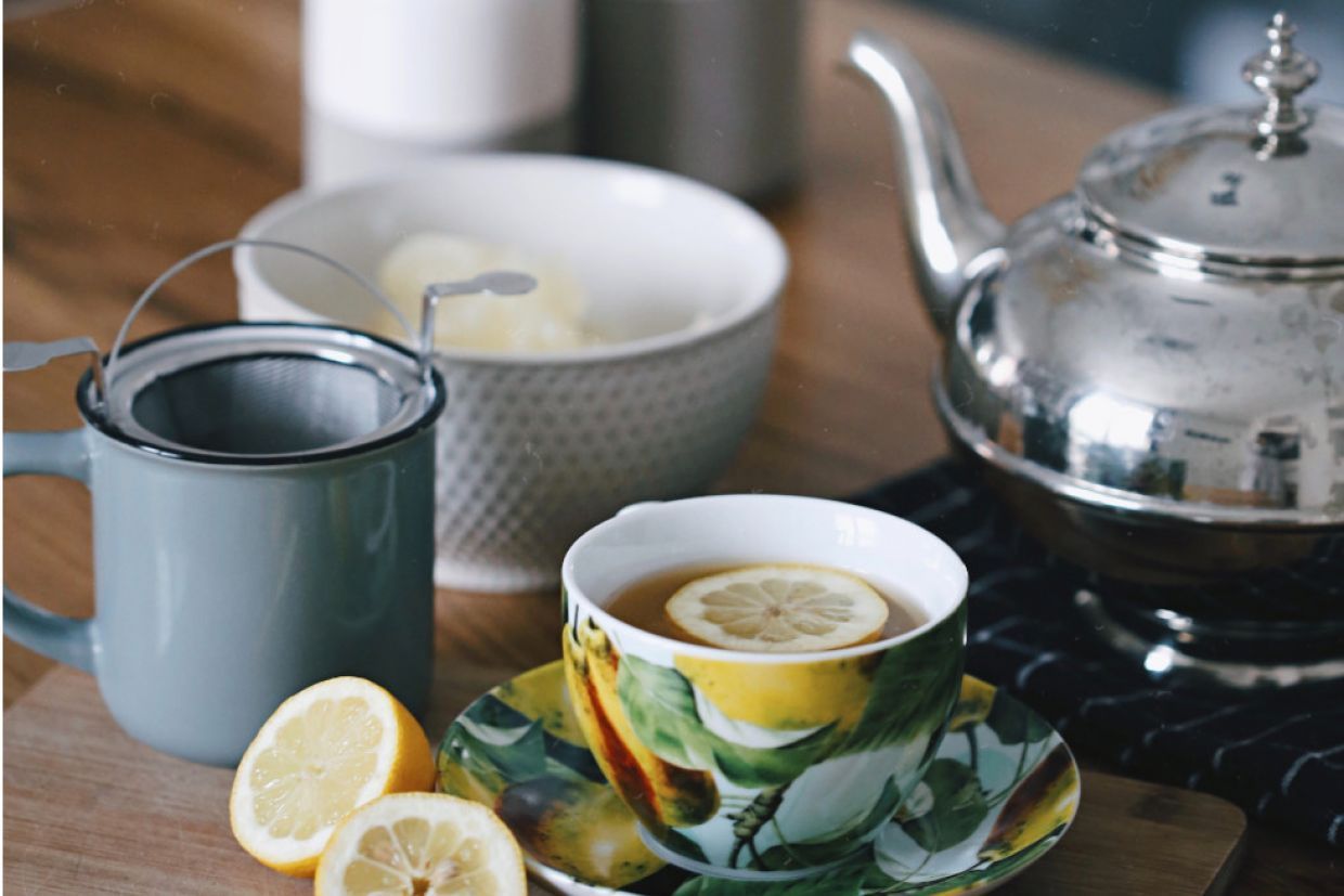 tea cup, mug, and tea pot arranged on a table with lemons