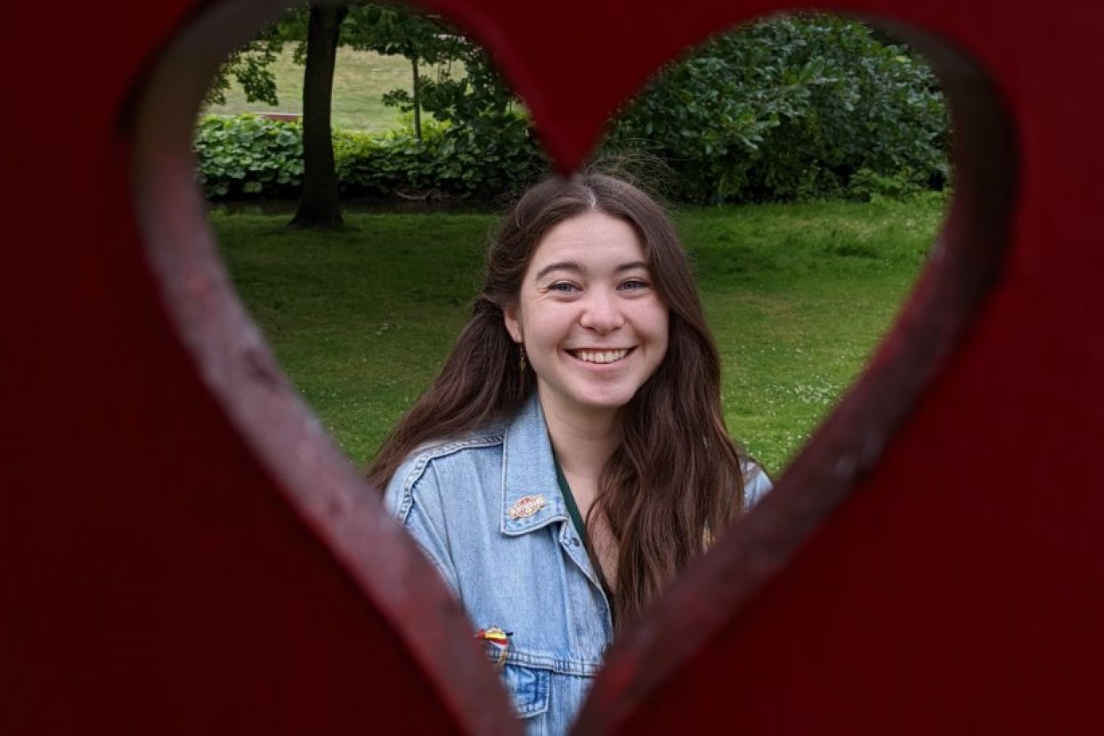 A girl smiling behind a heart-shaped hole