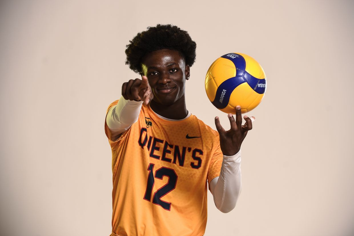 Volleyball player #12 with ball, pointing at camera 