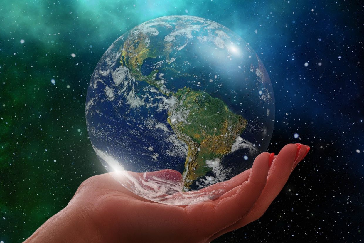 A replica of the world sitting in a person's hand, in space