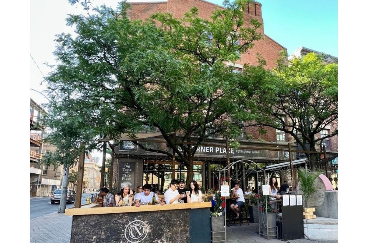 View of the Corner Place restaurant from the patio looking into the front of the restaurant with a tree in the middle of the patio
