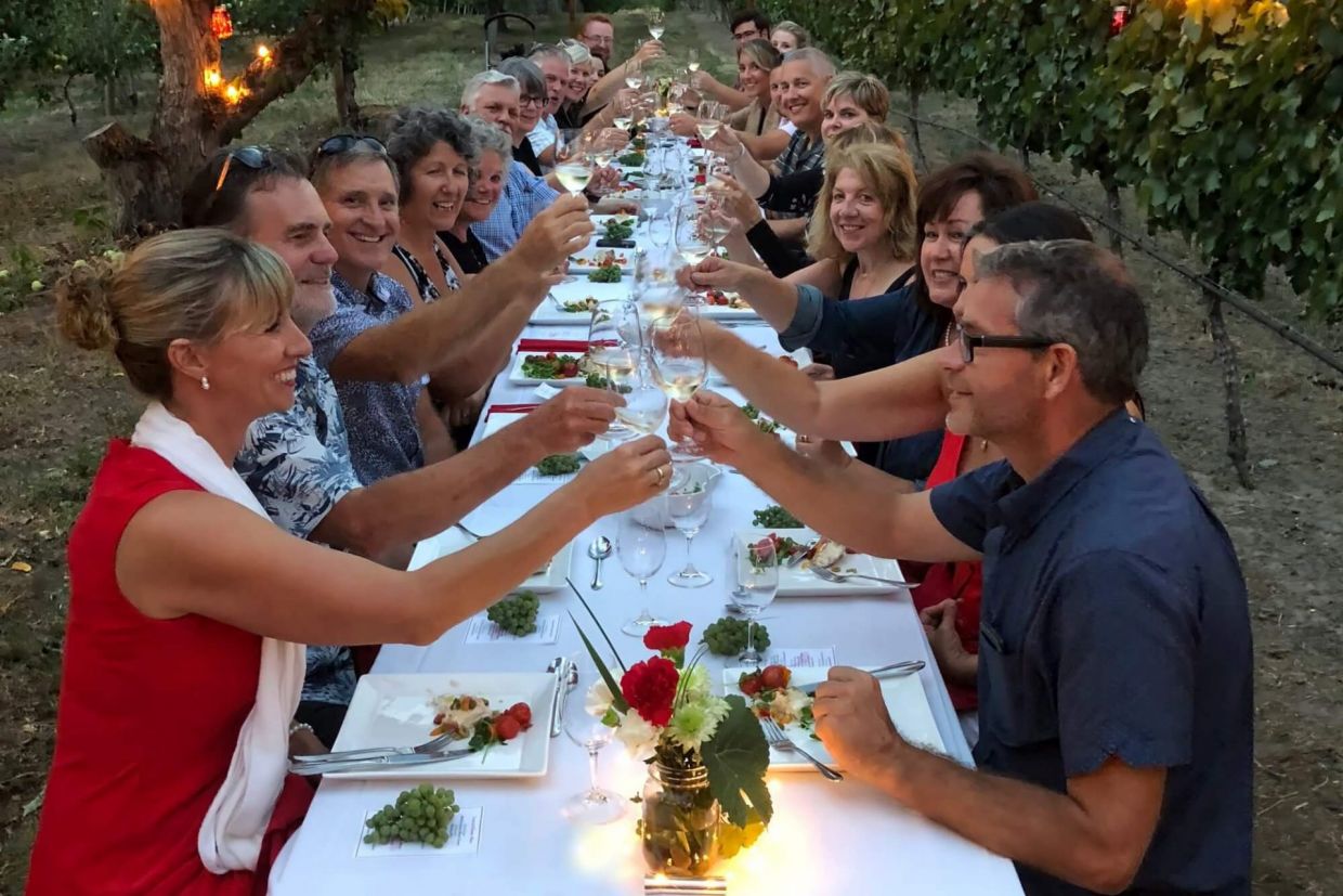 People picnicing and toasting glasses in an orchard