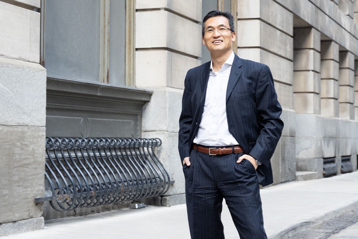 William Chung standing outside an old building in Toronto, with his hands in his pockets.